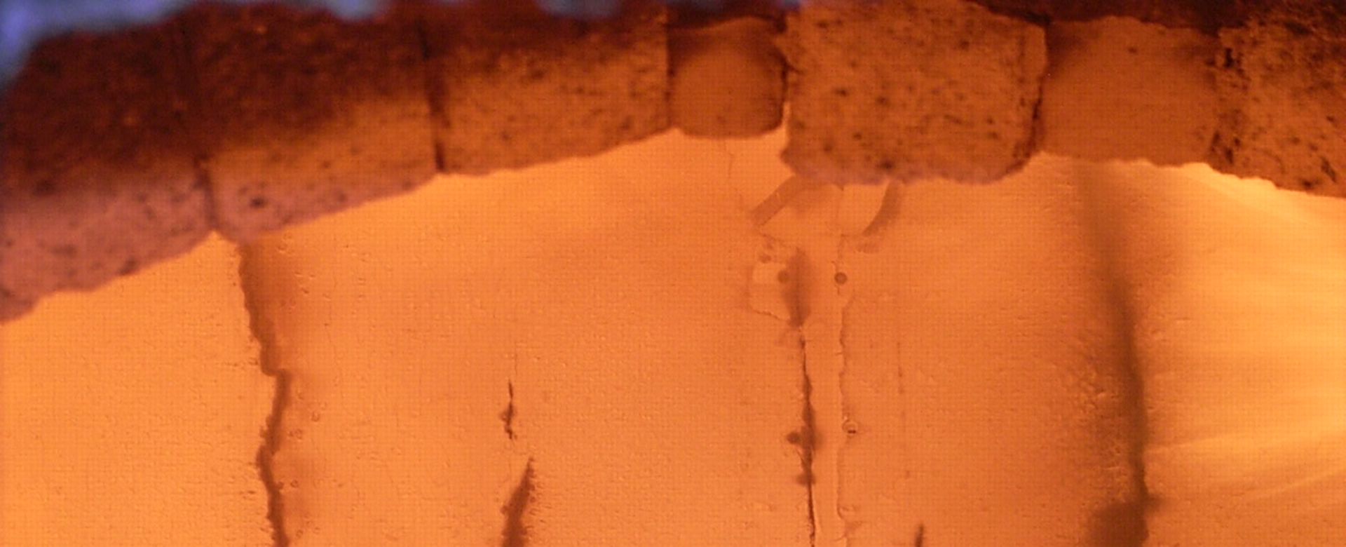Blick auf ein hellorange erleuchtetes Holzbauteil durch das Sichtfenster bei einer Brandprüfung.