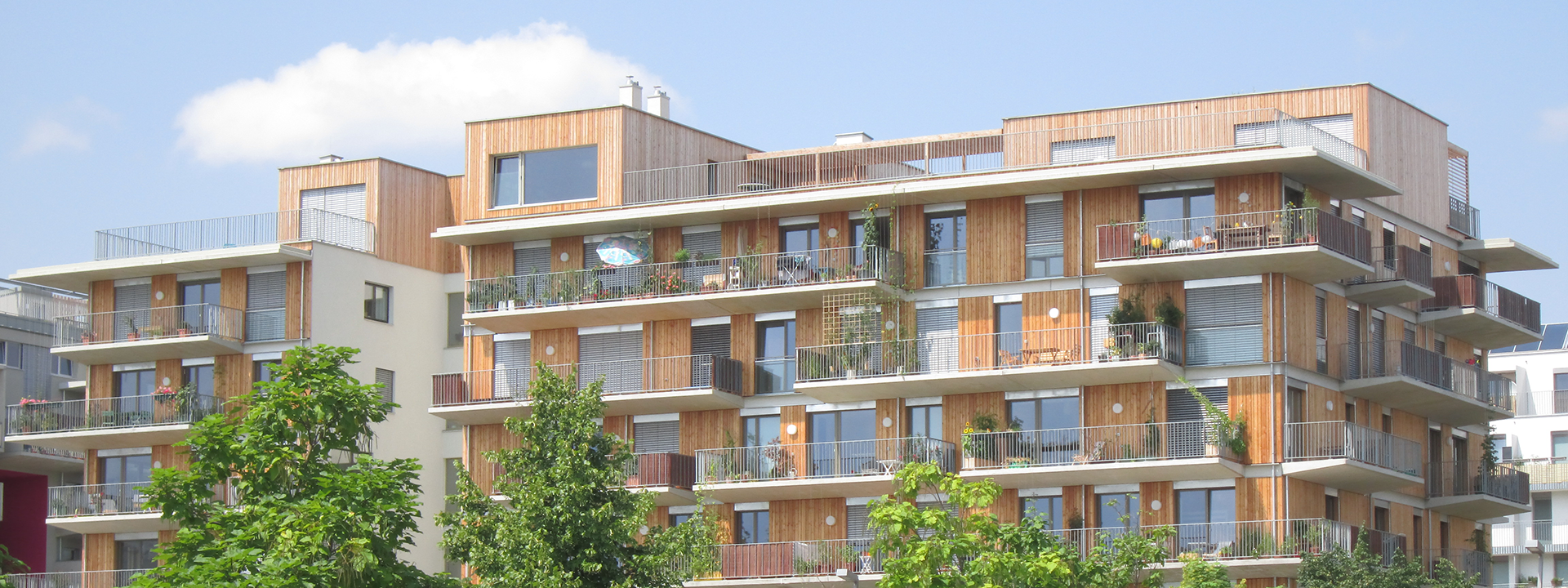 Mehrparteienhaus mit einer Holzfassade an einem freundlichen Frühlingstag.